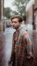 潮湿的街道上，一位穿着格子衬衫的时尚男子肖像，充满城市休闲氛围