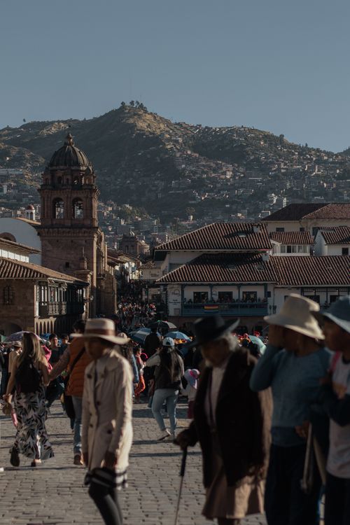Free Vibrant street activity in Cusco, Peru with a view of historic architecture against the mountainous backdrop. Stock Photo