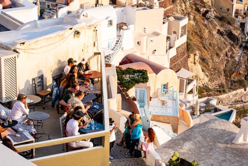 Free Vibrant terrace scene overlooking Santorini's iconic architecture during a warm summer sunset in Fira, Greece. Stock Photo
