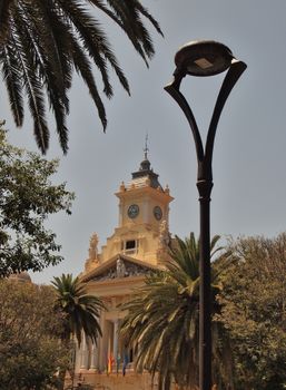 Historical architecture amidst palm trees in Málaga, Spain, showcasing classic Andalusian style.