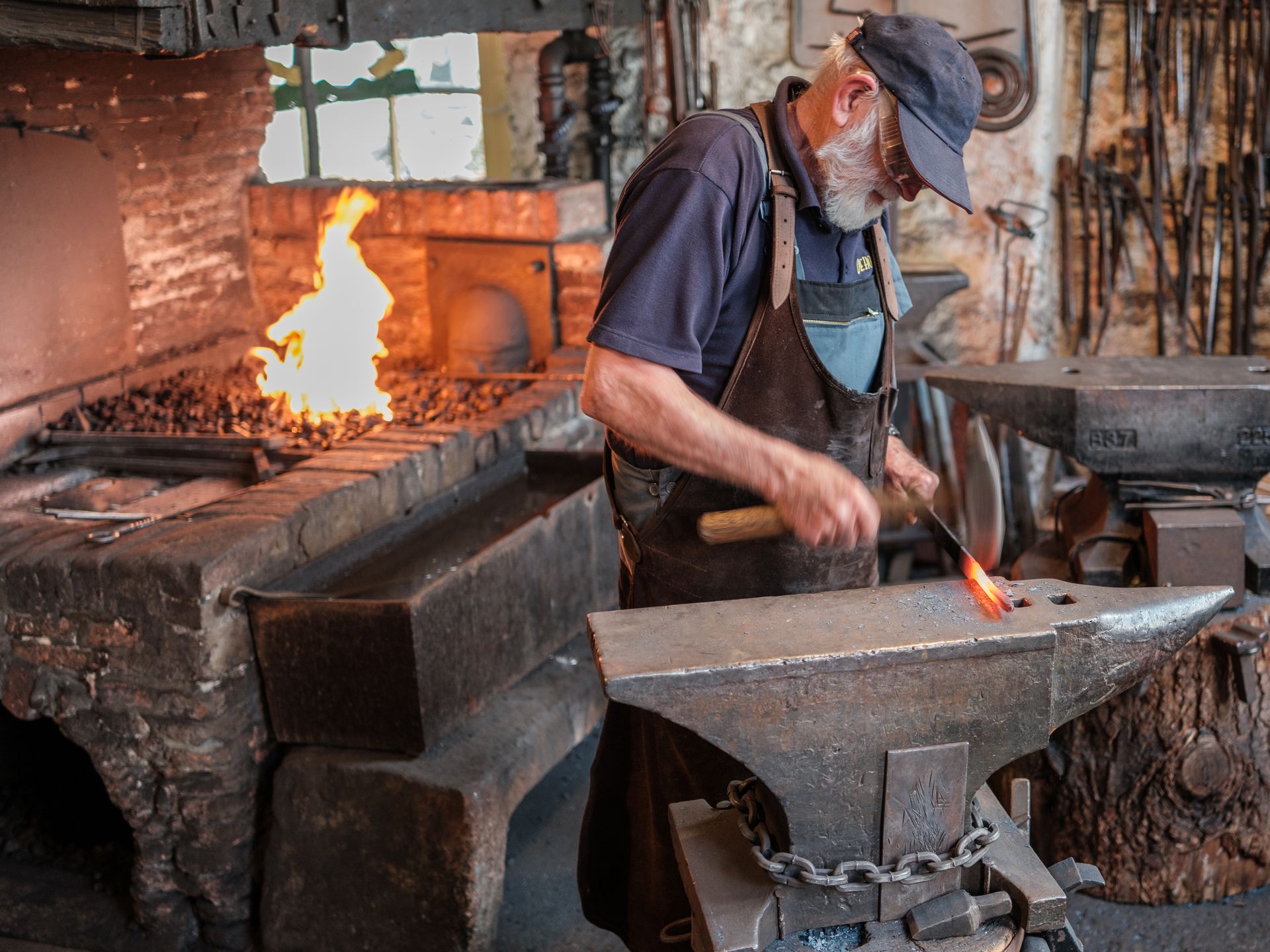 A skilled blacksmith working with fire and metal in a traditional forge setting.
