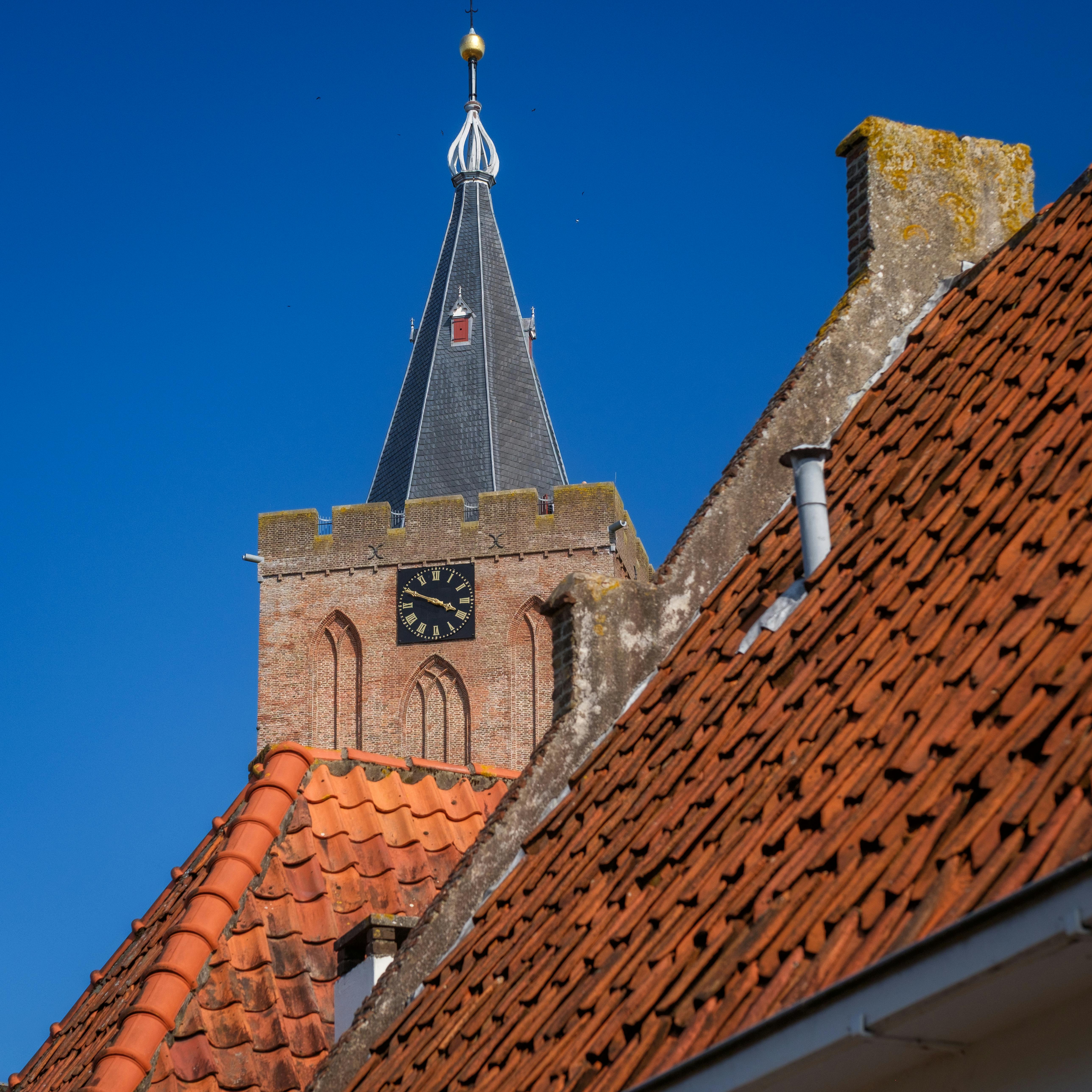 A stunning gothic church tower with a clock against a vibrant blue sky.