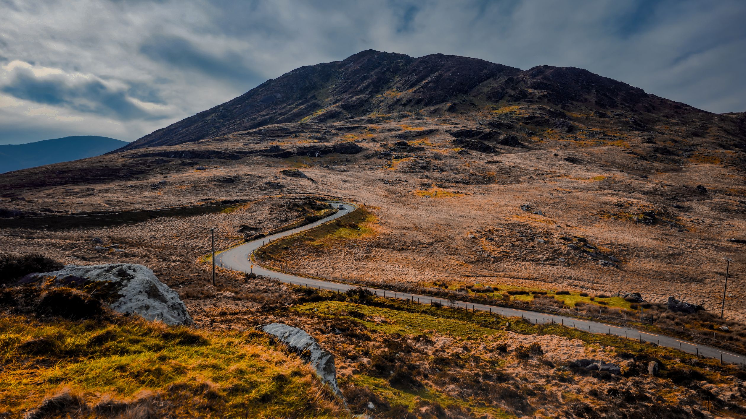 Sweeping view of a winding road through the picturesque Irish landscape with rocky hills.