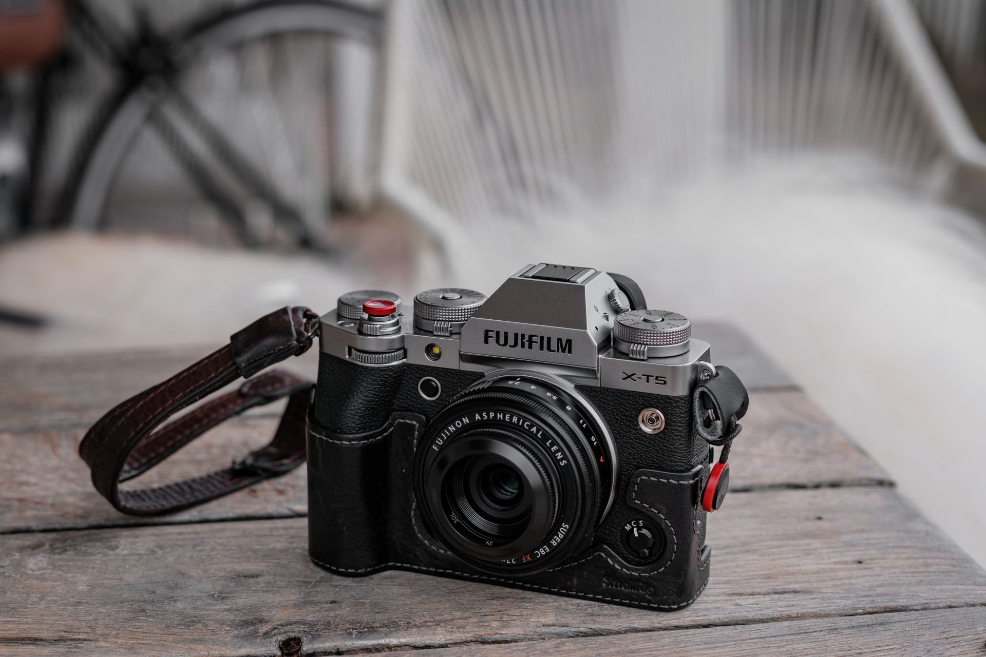 A stylish Fujifilm X-T5 camera with strap on a rustic wooden table, perfect for photography enthusiasts.