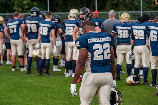 Football team players in helmets and uniforms preparing on the field.