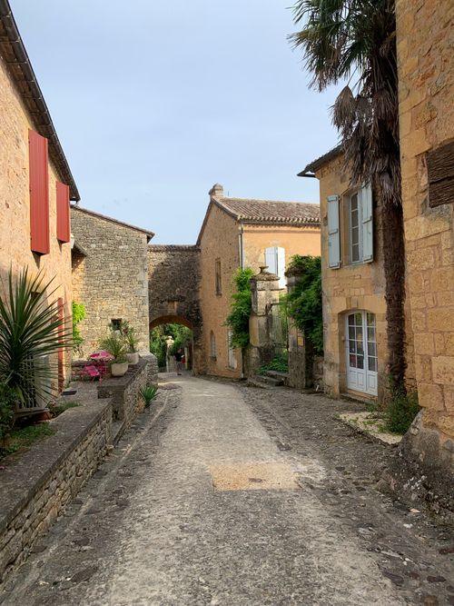 Free Picturesque street view of a medieval village in Biron, France with stone buildings and lush greenery. Stock Photo