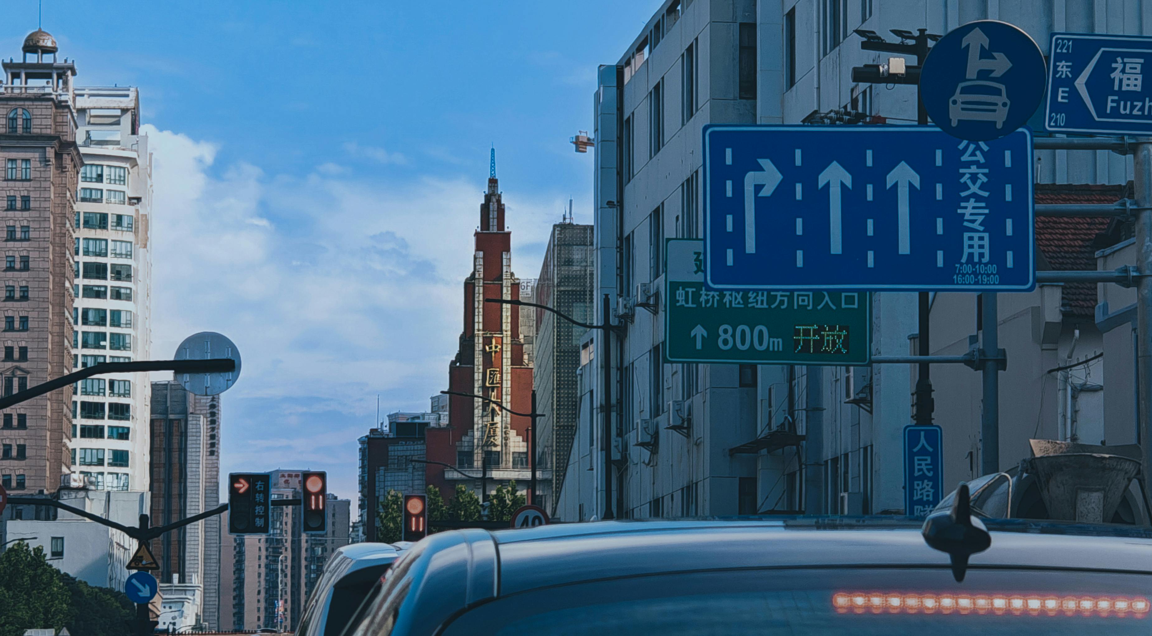 Urban scene with traffic signs, cars, and skyscrapers under a blue sky in a busy city street.