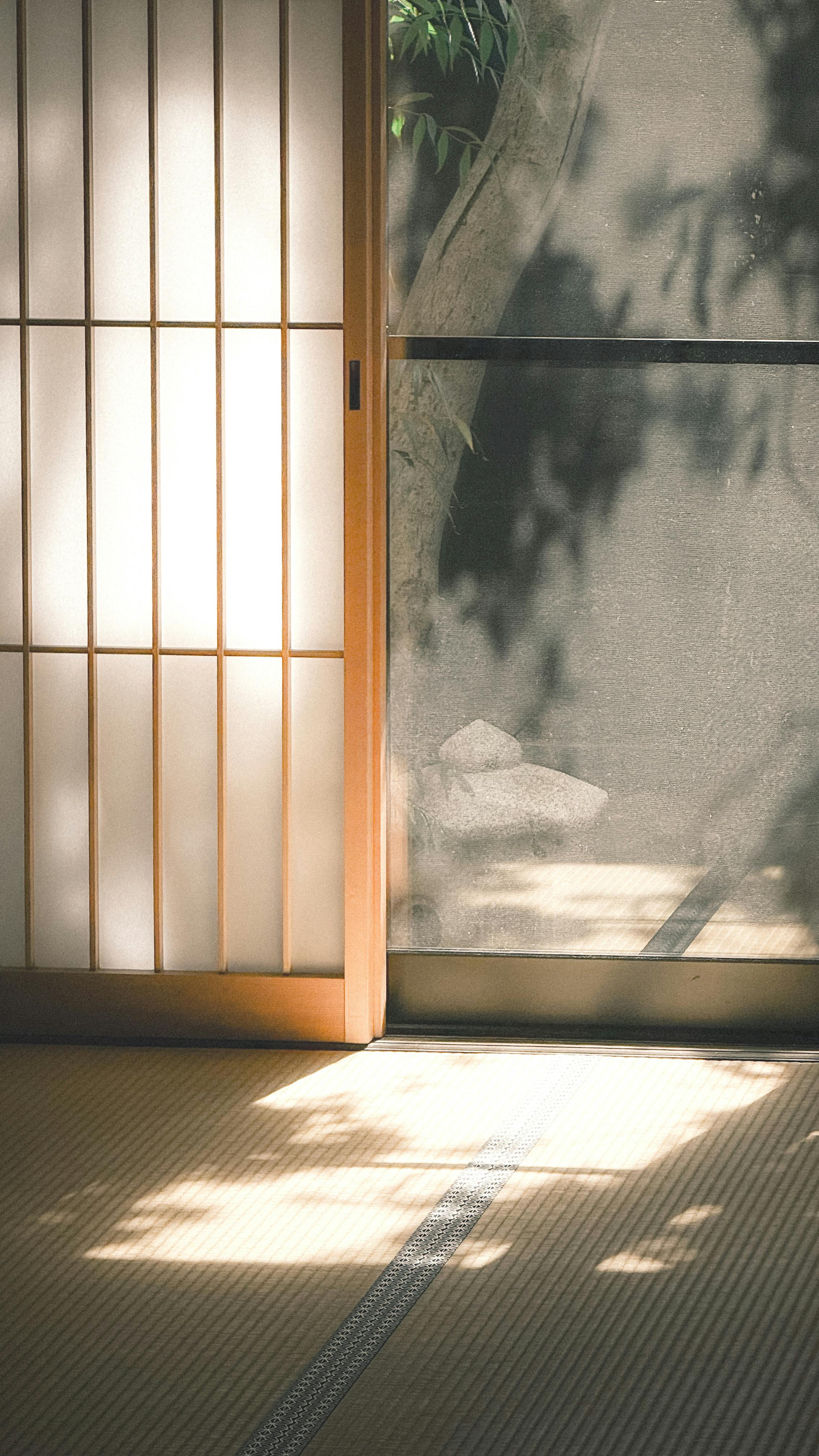 A serene Japanese-style room with shoji doors and sunlight streaming in, casting shadows.