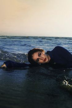 Captivating portrait of a woman lying on ocean waves, embracing nature's beauty.