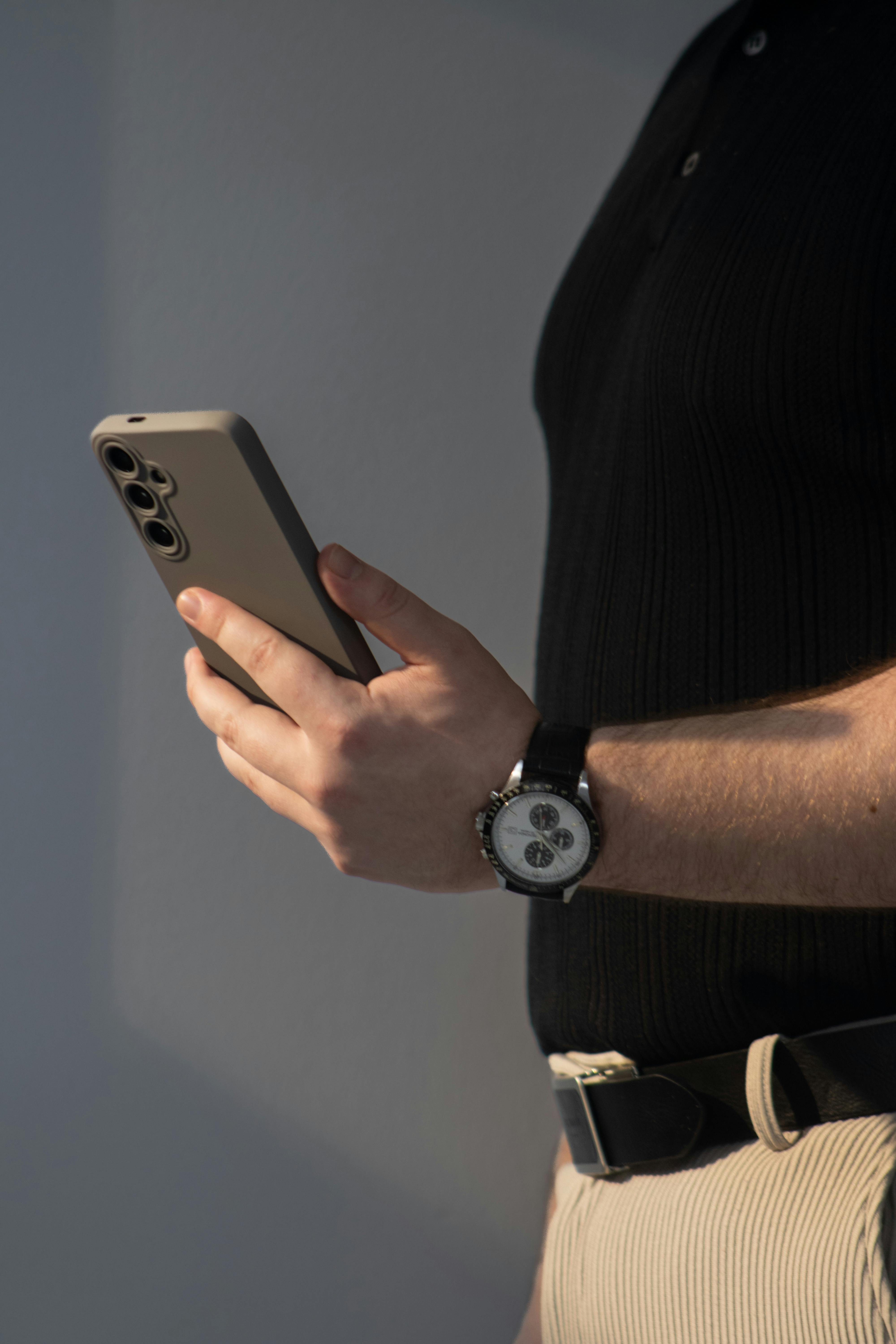 Gratuit Un bărbat îmbrăcat lejer își privește smartphone-ul în interior, etalând stil și tehnologie modernă. Fotografie de stoc