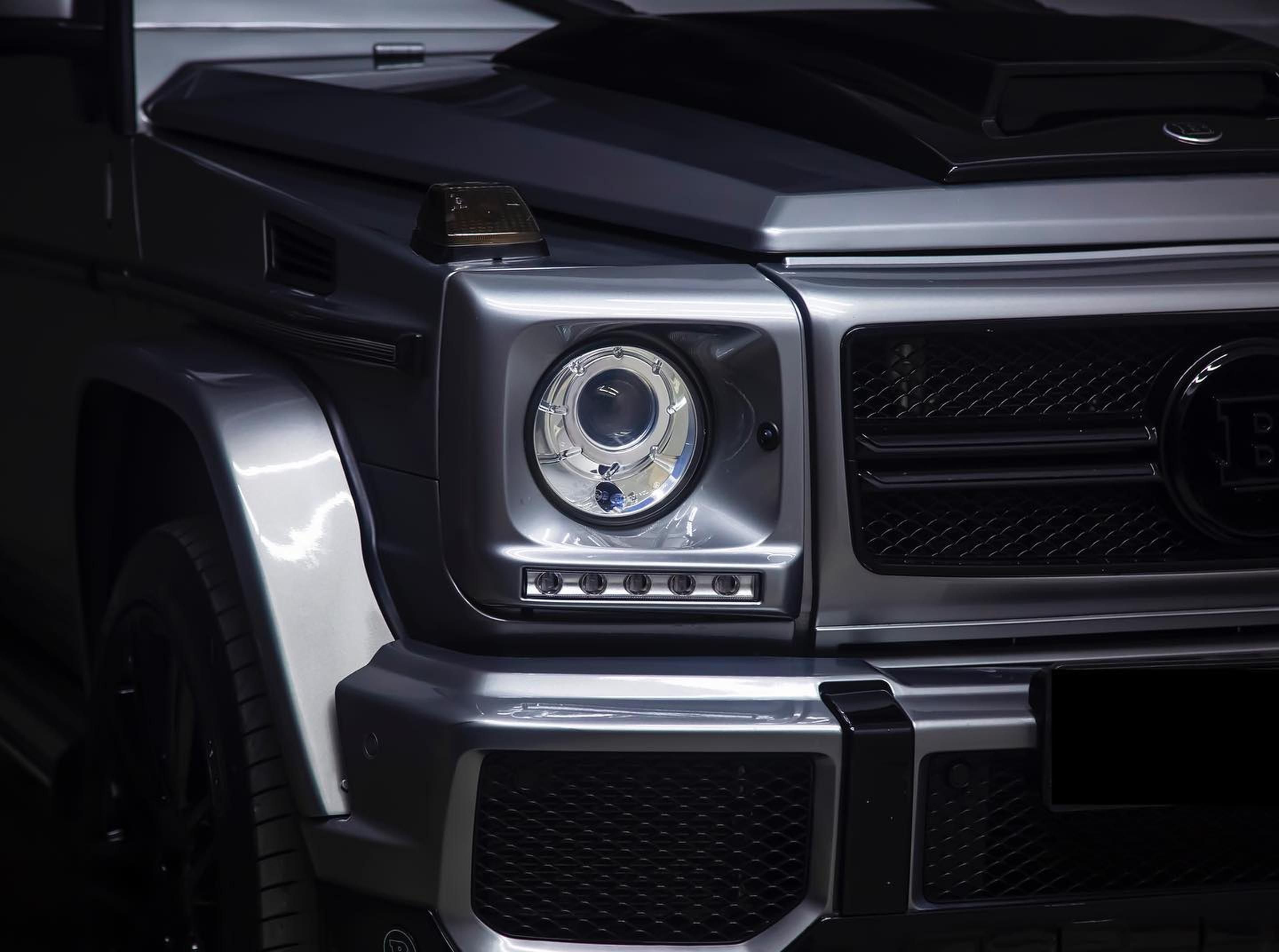 Detailed view of a luxury SUV's front headlight and grille, highlighting the design and contours.