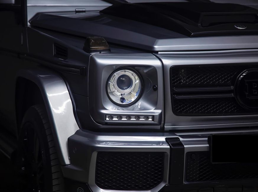 Detailed view of a luxury SUV's front headlight and grille, highlighting the design and contours.