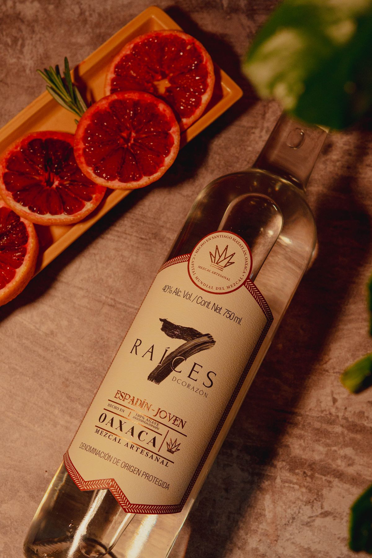 Artisan mezcal bottle with sliced blood oranges, highlighting traditional Mexican spirits.