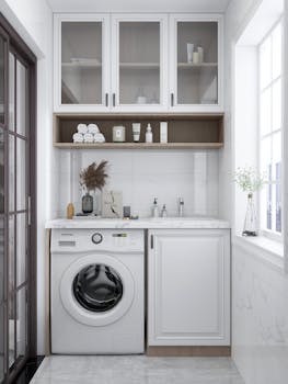 A sleek and bright laundry room featuring a washing machine, cabinets, and natural decor.