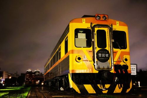 Free A vibrant yellow and orange train captured under city lights in Kaohsiung, Taiwan. Stock Photo