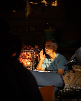An Indian fruit vendor illuminated by sunlight in a bustling street market.