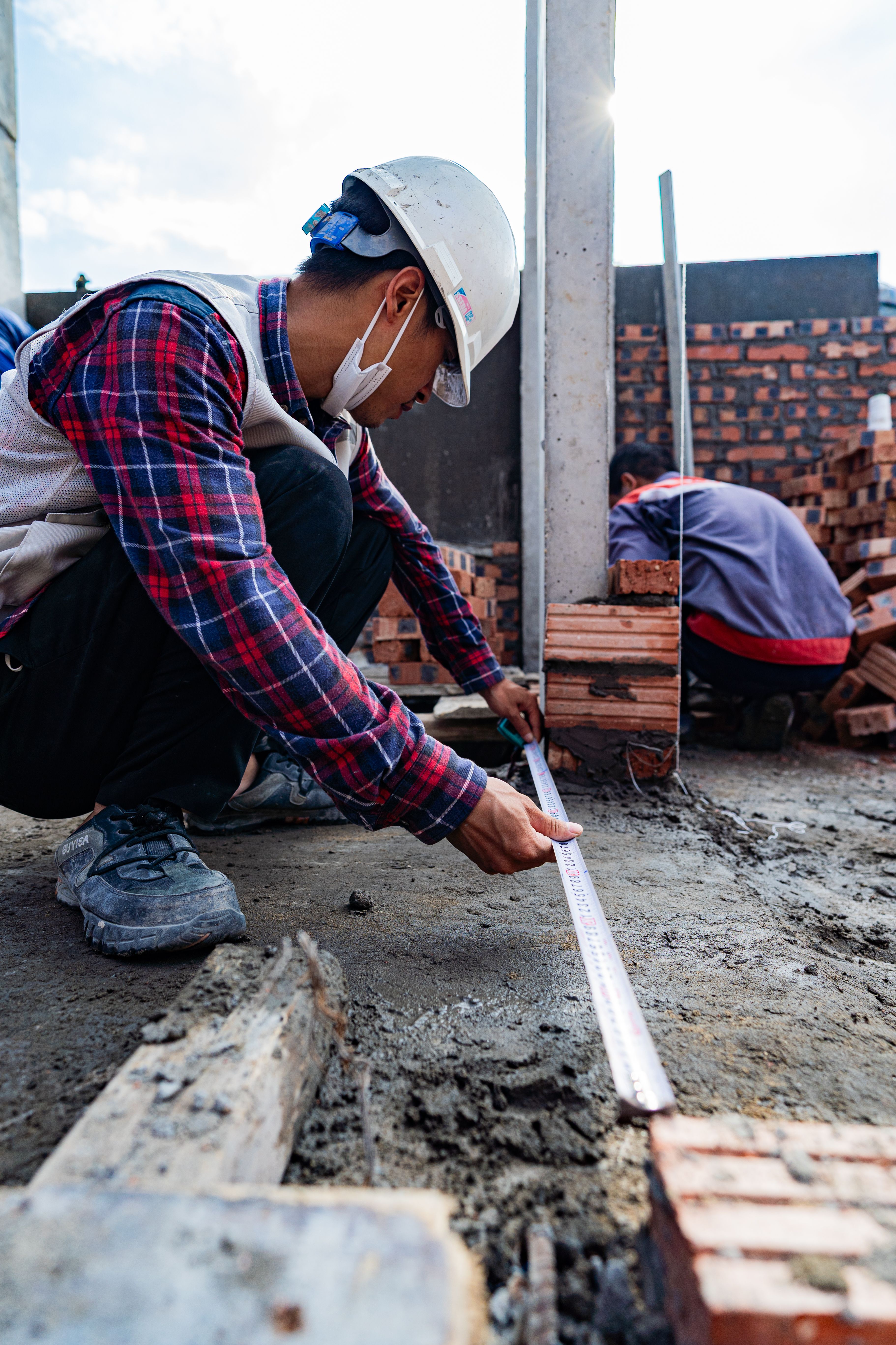 Two construction workers measuring bricks on a construction site in Hải Phòng, Vietnam.