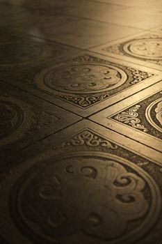 Close-up of ornate Vietnamese floor tiles with detailed designs and warm lighting.