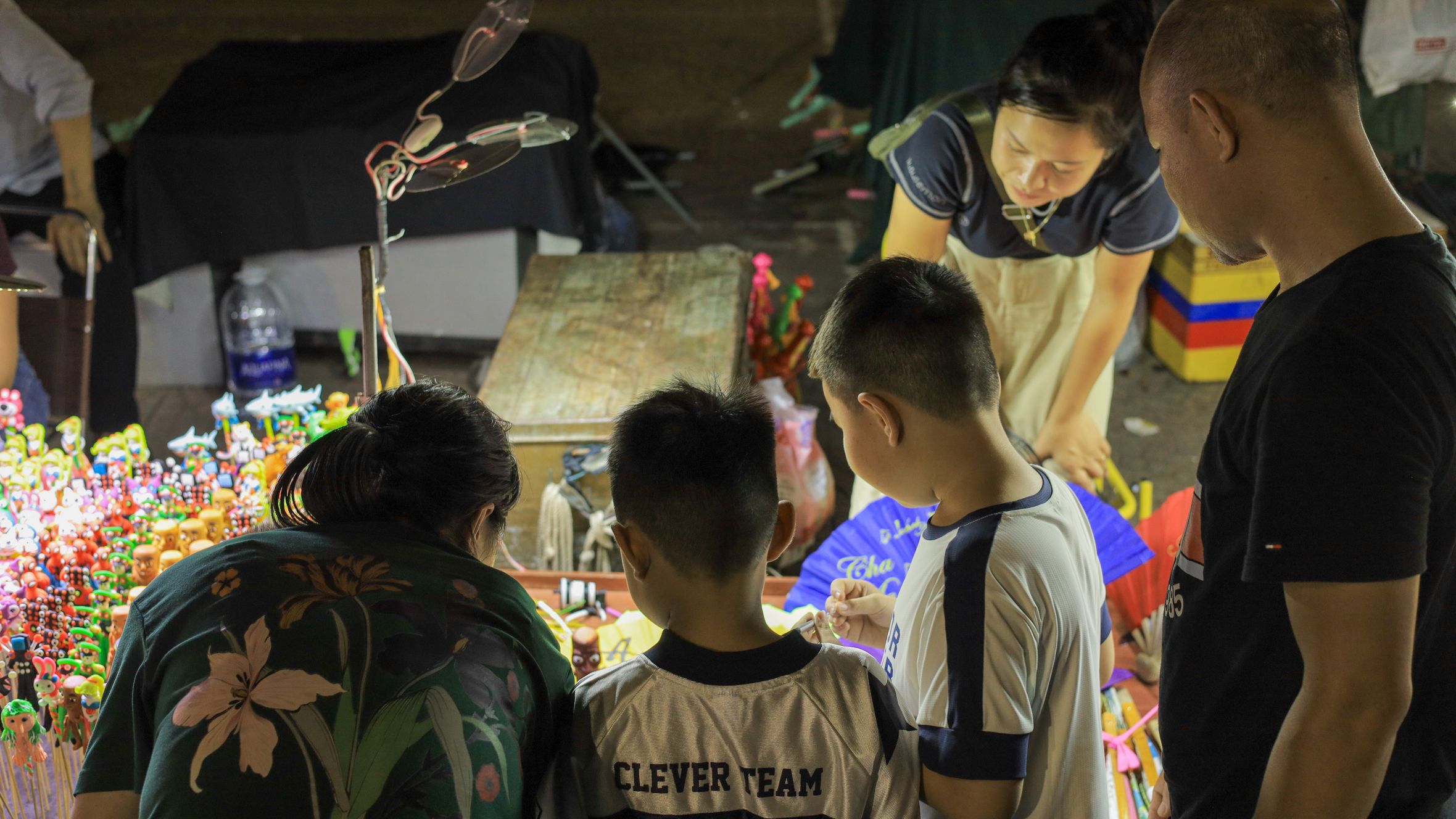 Family shopping for toys at a vibrant night market in Vietnam, enjoying local culture.