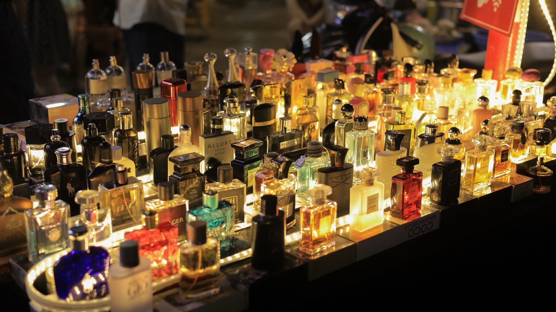 A colorful display of perfume bottles lit up at a night market in Vietnam, capturing the lively atmosphere.
