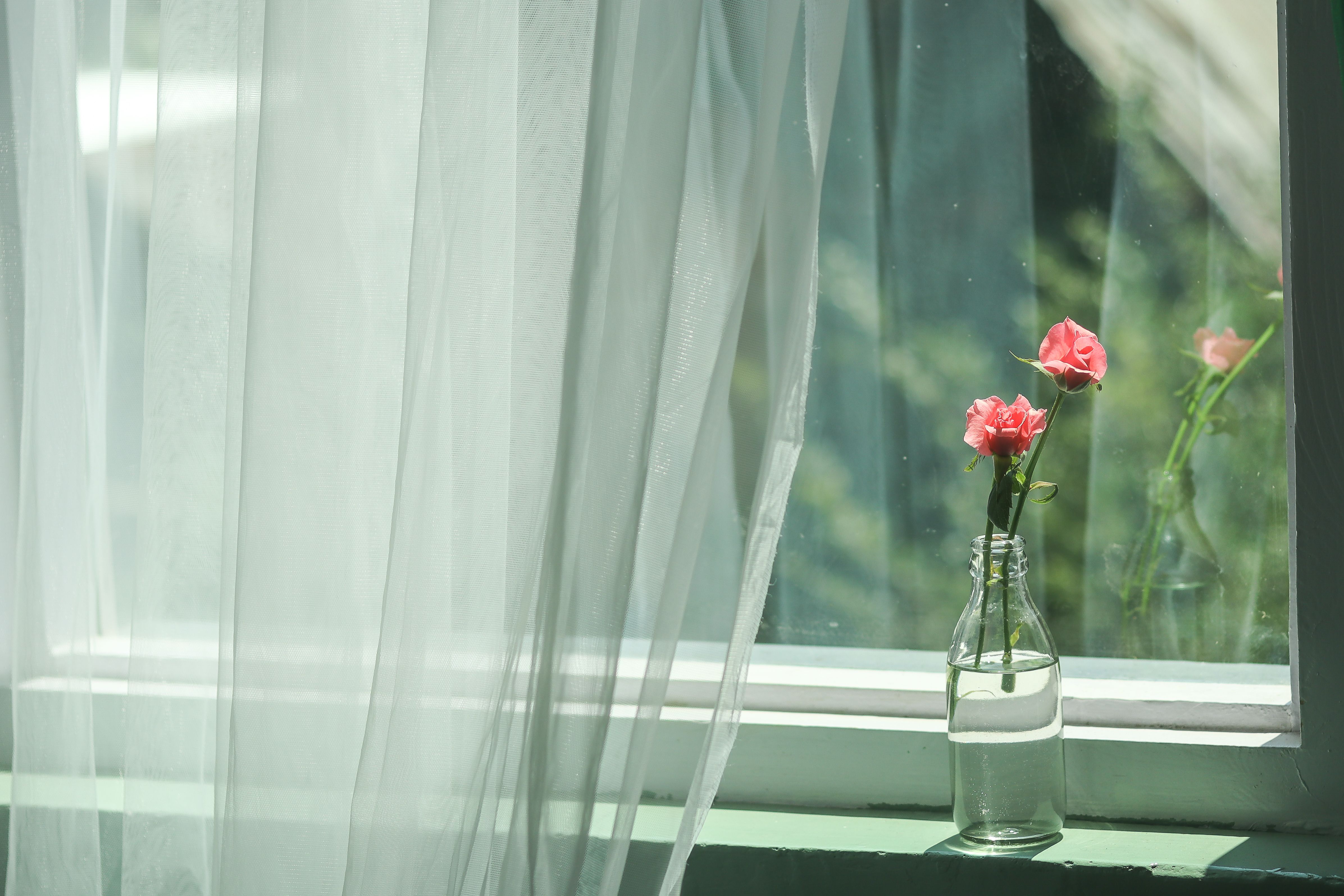 Geurtuingordijnen met bloemenpatroon in een zonnige kamer.