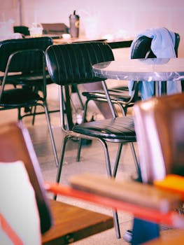A cozy vintage cafe interior featuring empty black chairs and tables with a warm ambiance.