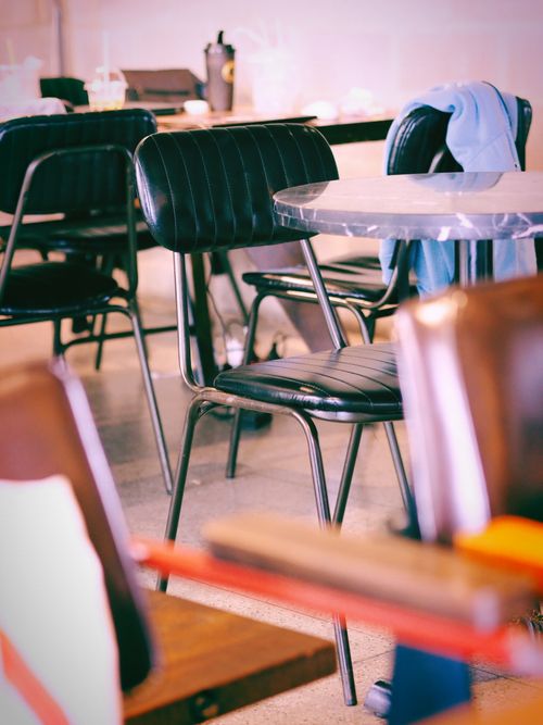 Free A cozy vintage cafe interior featuring empty black chairs and tables with a warm ambiance. Stock Photo