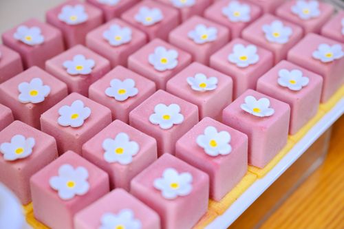 Free Rows of pink square pastries topped with white floral icing, creating a charming treat. Stock Photo