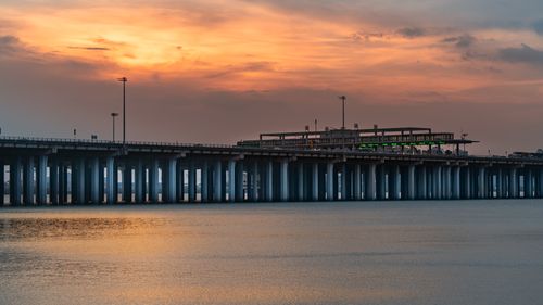 Free A stunning sunset illuminates a city bridge over calm waters, creating a picturesque urban scene. Stock Photo