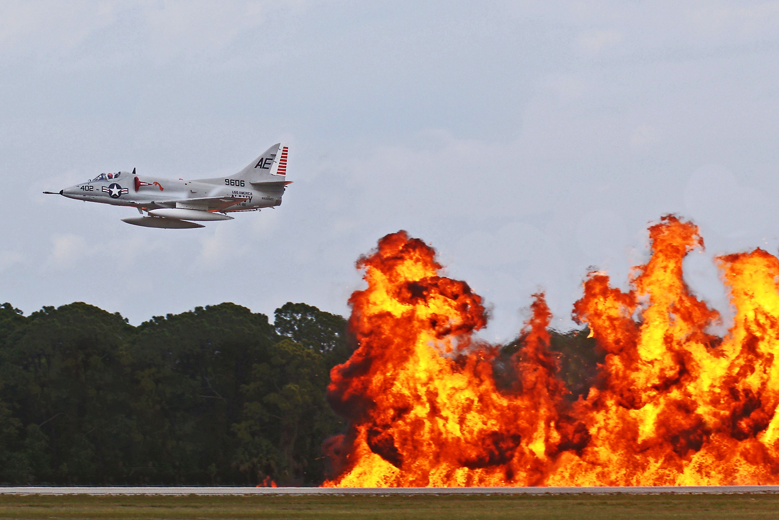A military jet flies over fiery explosions during an airshow in Titusville, Florida.