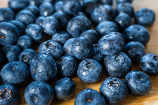 Close-up view of fresh blueberries on a wooden surface, showcasing their vibrant color and texture.