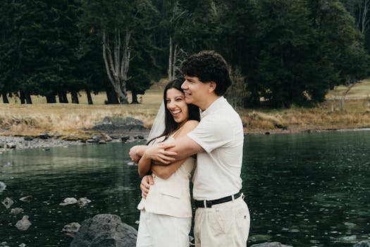 A couple sharing a joyful embrace by a serene lake in Patagonia, Argentina.