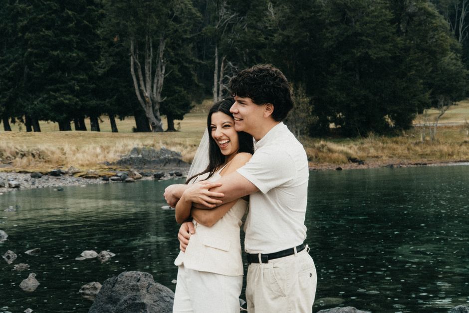A couple sharing a joyful embrace by a serene lake in Patagonia, Argentina.