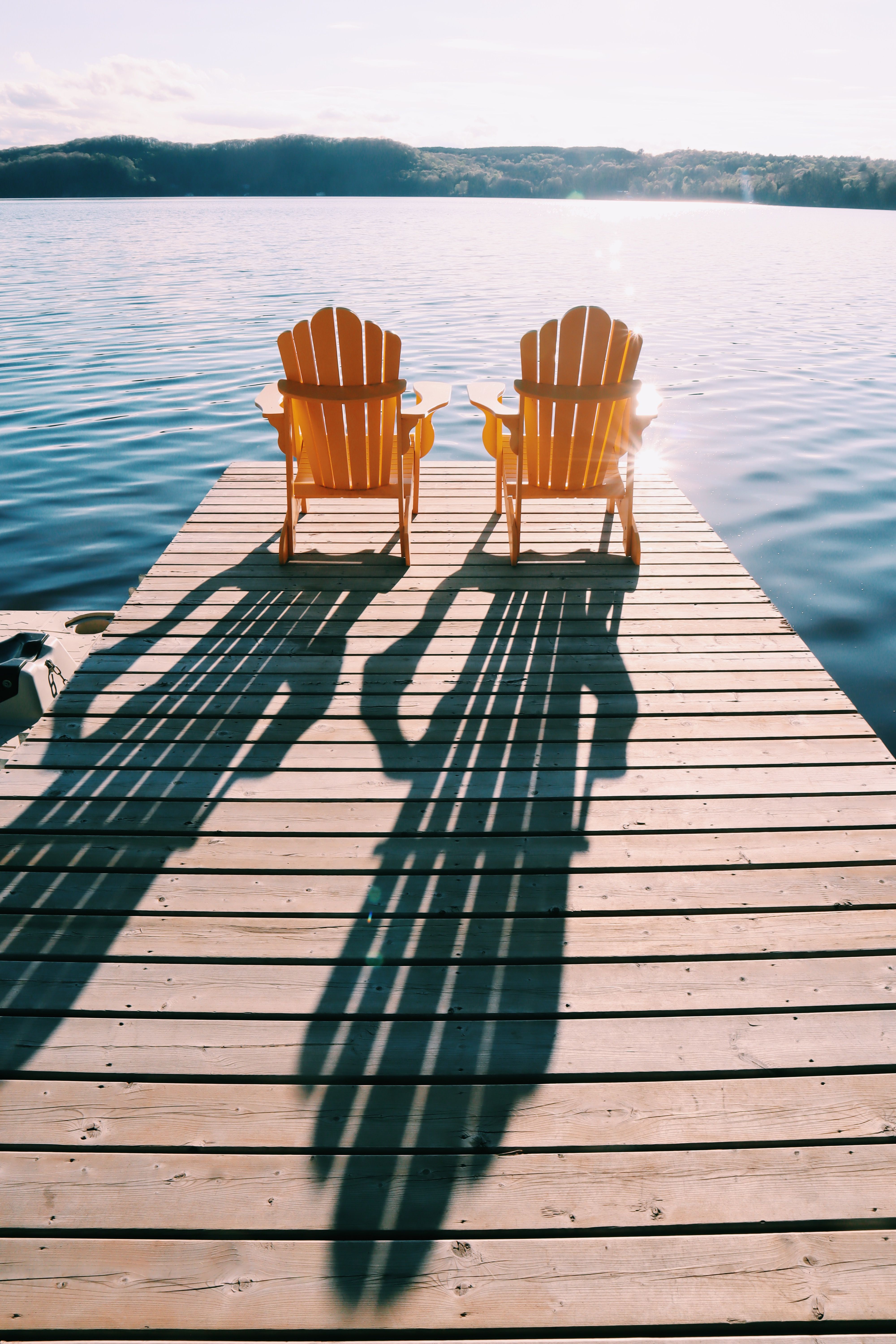 Two Adirondack Chairs on Sunny Lakeside Dock · Free Stock Photo