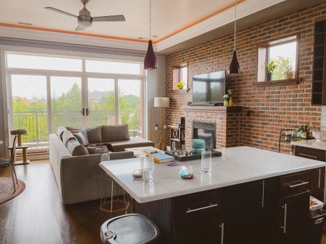 Spacious living room featuring a brick wall, fireplace, and large windows with outdoor view.