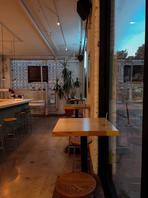 Free Charming cafe interior with warm lighting, wooden tables, and window seating. Perfect for relaxing. Stock Photo