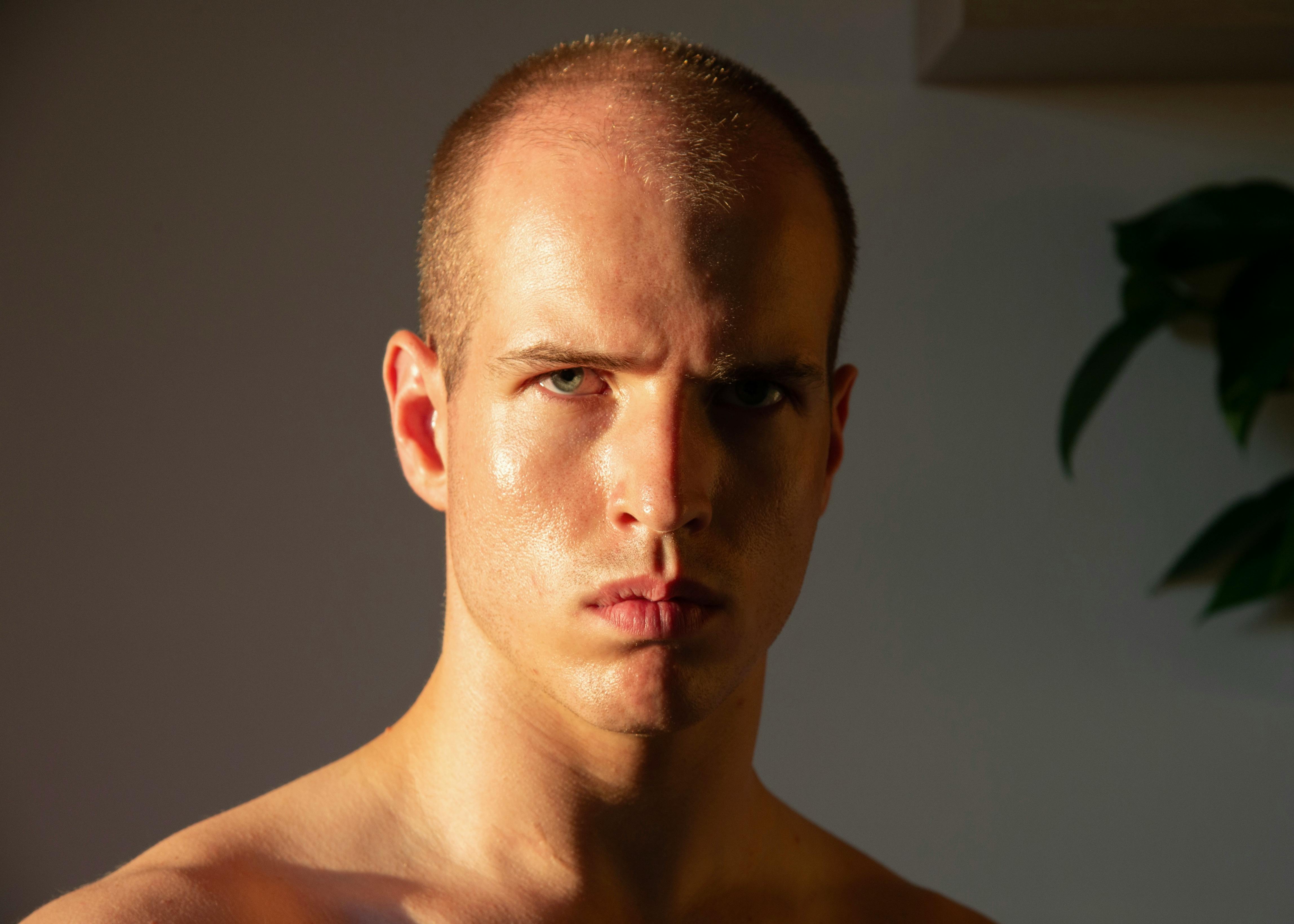 bezplatná Detailní portrét vážného mladého muže v intenzivním osvětlení se stínovým efektem. Základová fotografie