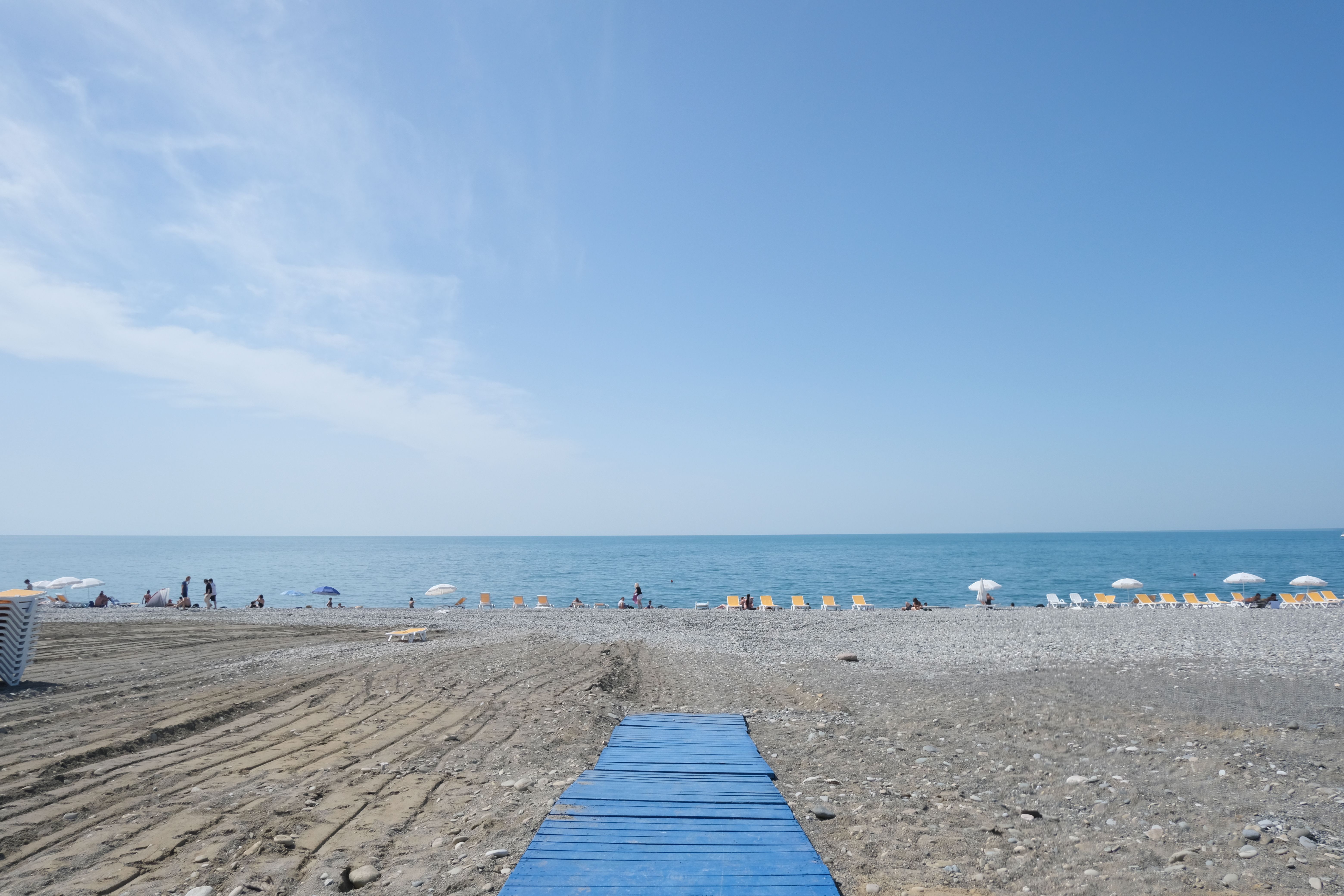Idyllic Batumi Beachfront With Sunbeds, Umbrellas, And A Serene Blue Sky Over The Black Sea.