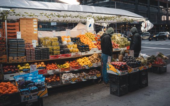 Fresh fruits and vegetables at a bustling street market in New York City during daytime.