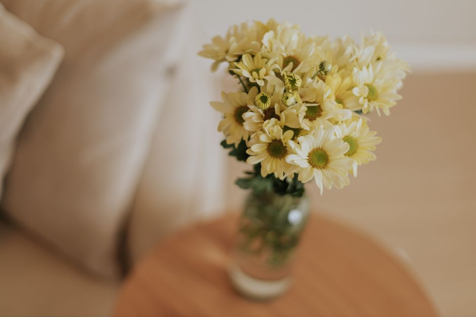 A serene arrangement of yellow daisies in a vase, perfect for minimalist interiors.