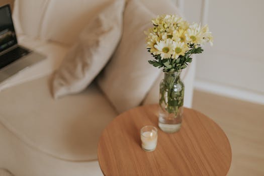 Elegant home interior showcasing a minimalist setting with daisies and a warm candle on a wooden table.