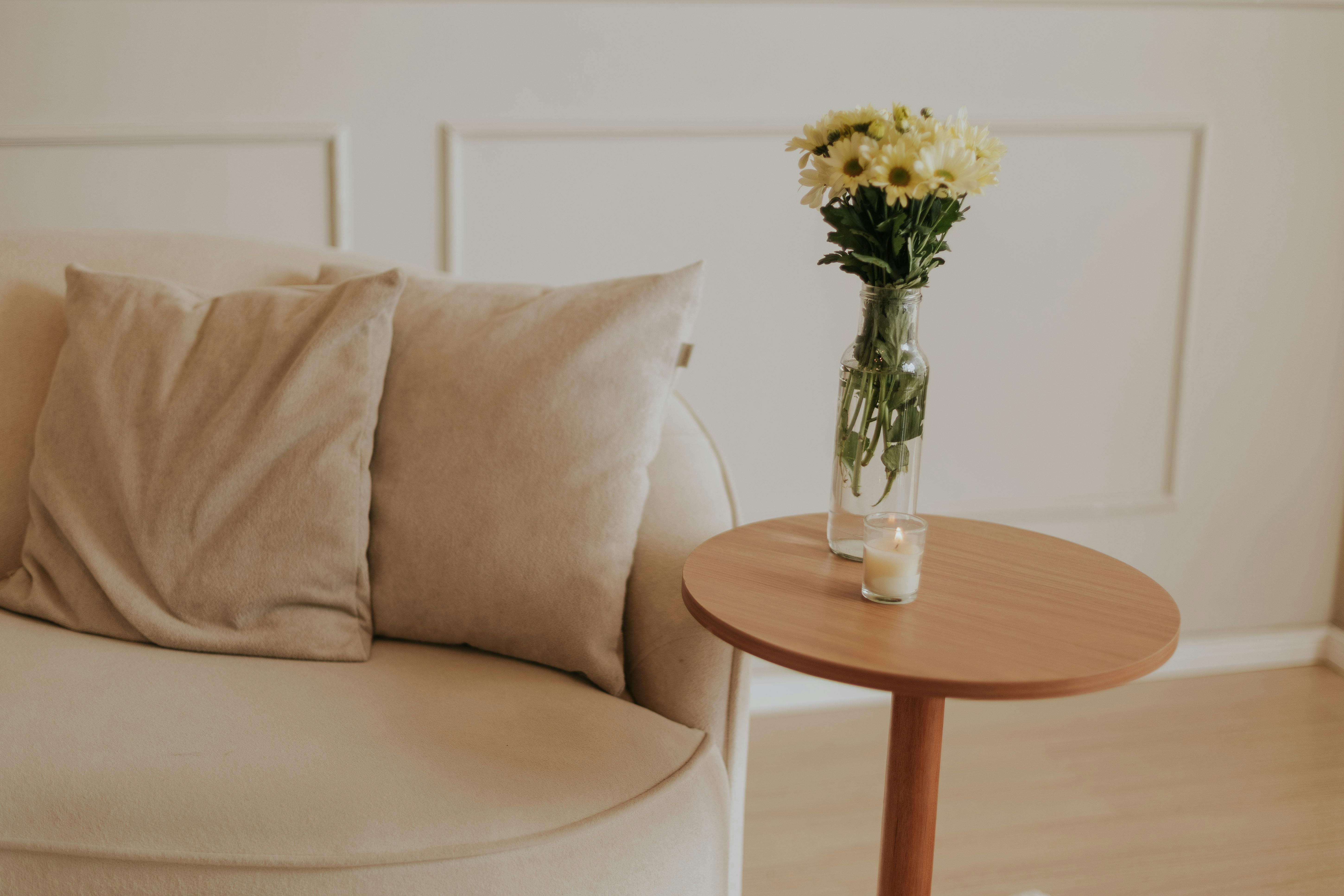 A peaceful interior with a minimalist aesthetic featuring a beige sofa, wooden table, and flowers.