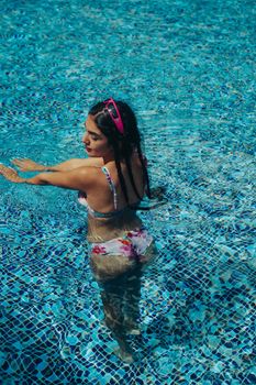 Young woman enjoying a swim in a colorful outdoor pool during summer.