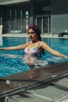 A woman enjoying a sunny day in a modern outdoor swimming pool.