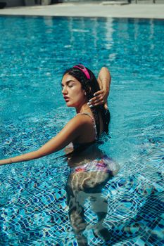 Woman enjoying a sunny day in a vibrant outdoor pool.