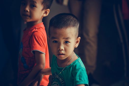 Two young boys indoors with curious expressions and soft lighting, capturing a moment of innocence.