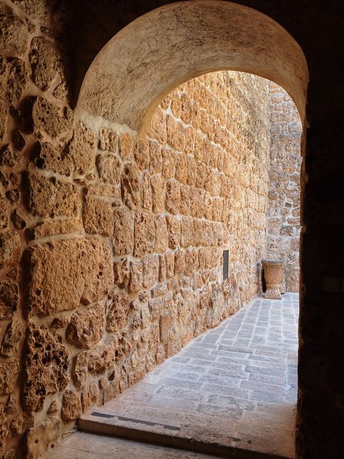 Free Sunlit stone archway leading to an ancient courtyard. Rustic charm and historical architecture. Stock Photo