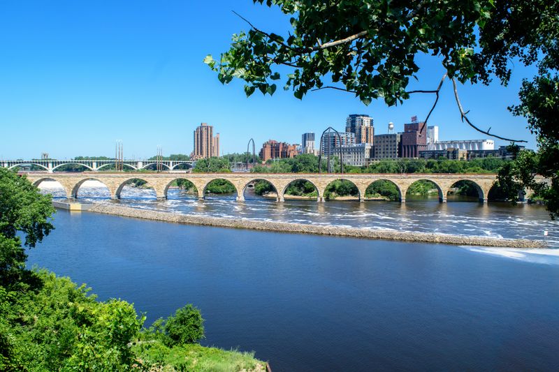 A stunning view of the Stone Arch Bridge and Mississippi River in Minneapolis on a clear summer day.