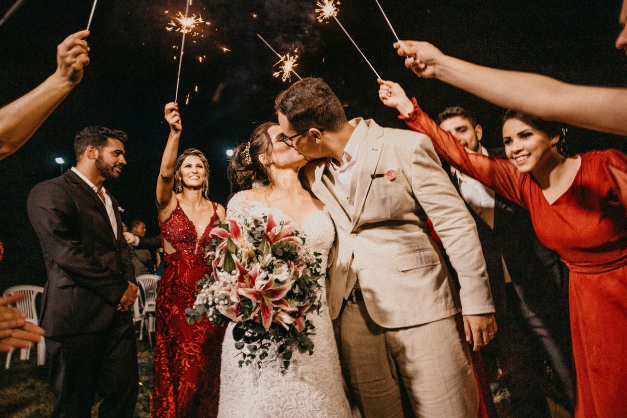 Newlywed couple kissing under sparklers surrounded by guests