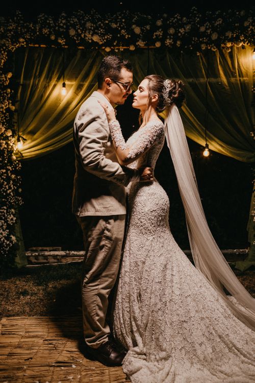 Free Elegant couple embraces under twinkling lights at their evening wedding ceremony. Stock Photo